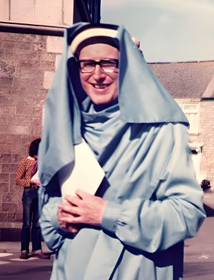 PHOTO: Ray Edwards 
                             standing outside in the sunshine, smiling, wearing 
                             his blue bardic robes and headdress.